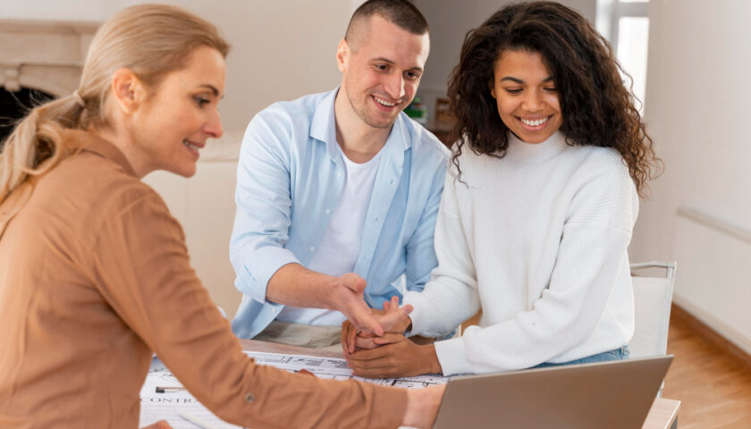 un couple souriant en rendez-vous avec un conseiller en gestion de patrimoine